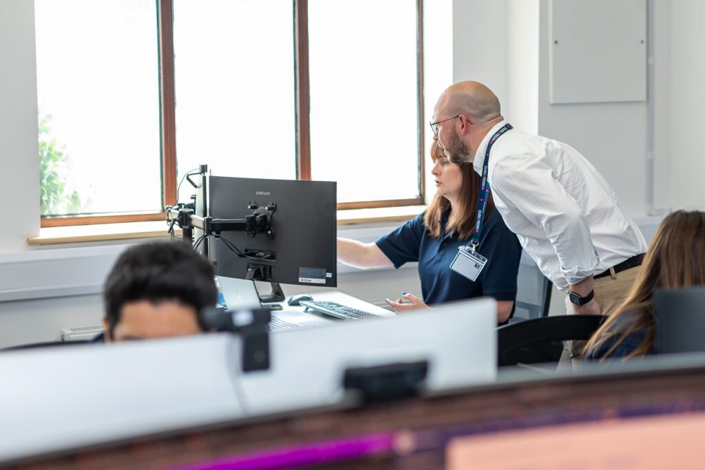 Colleagues talk in a busy IT office in Surrey
