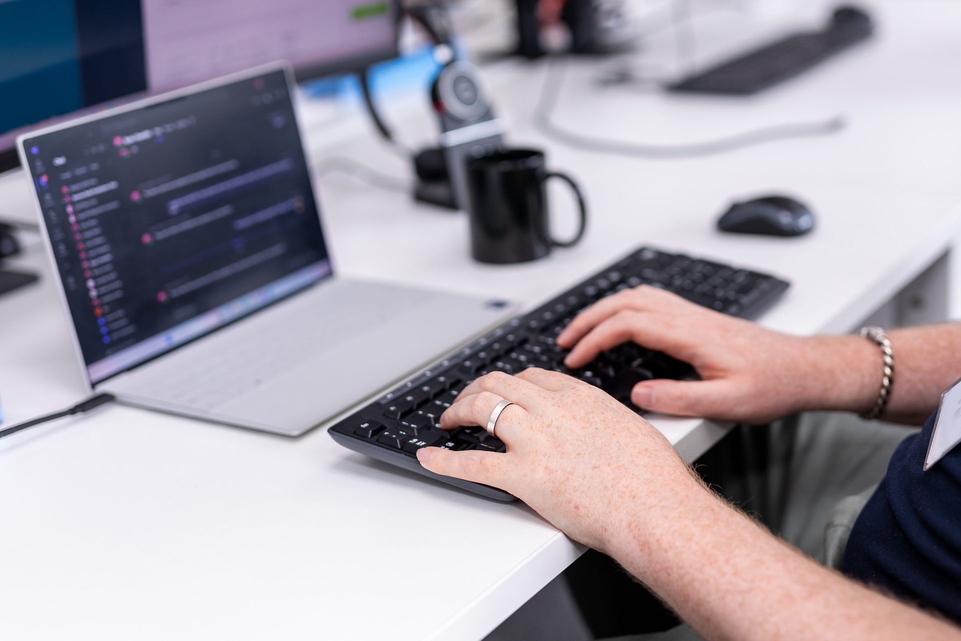 Laptop and keyboard on a desk with a CloudTech24 employee's hands in shot as they work at the keyboard